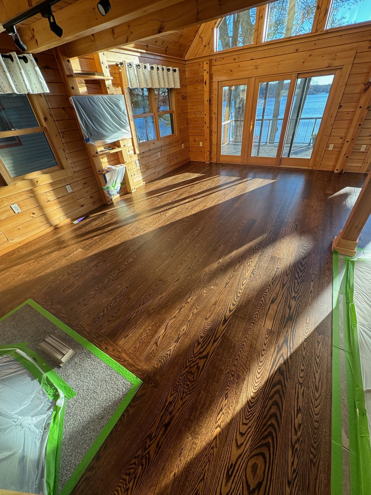 Killingly CT — finished lake room with dark stained hardwood floor, natural wood interior and lake view windows