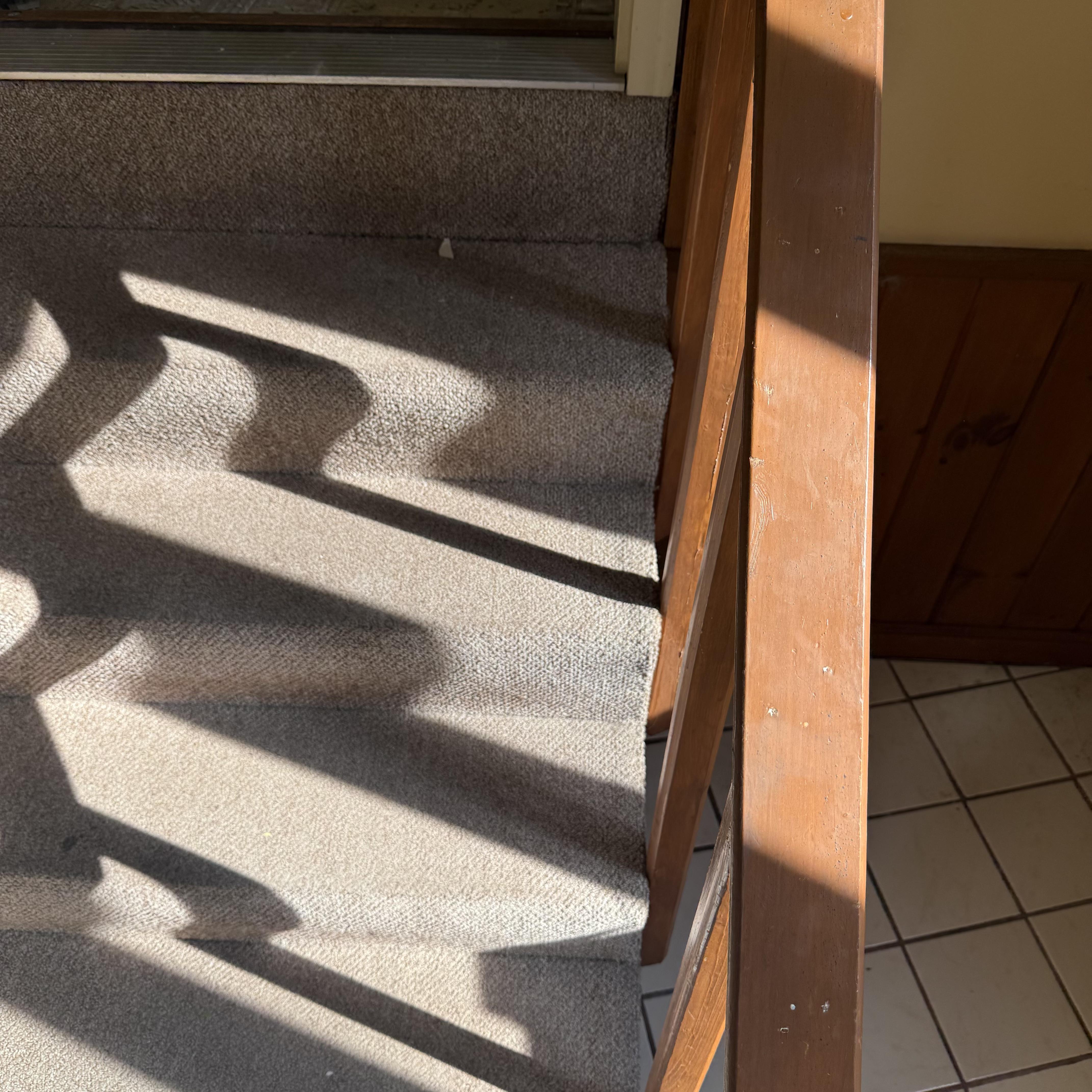 Before — carpet staples and worn tread surface before staircase remodel