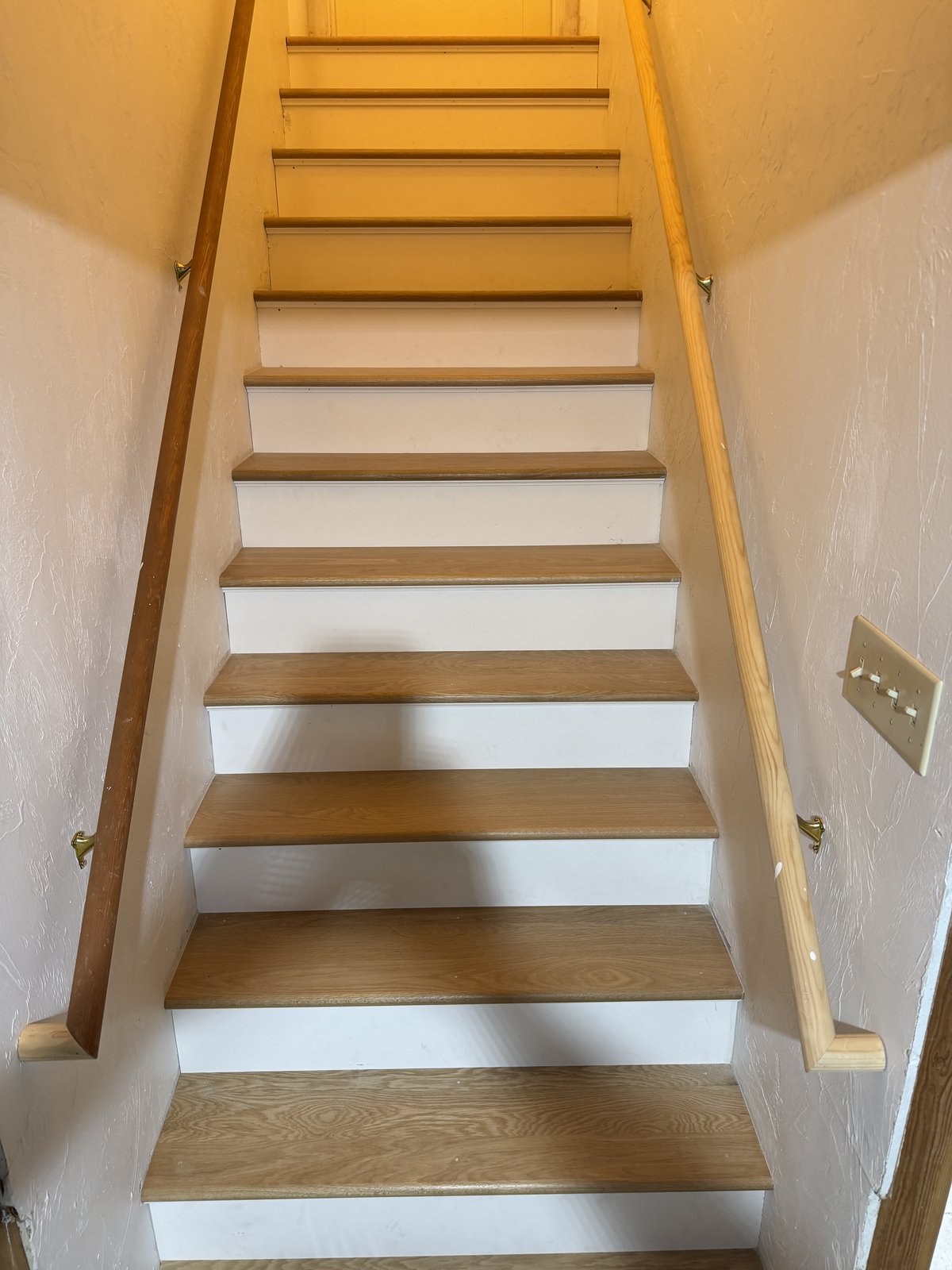 Cranston RI — finished white oak staircase craftsmanship detail showing treads, white risers, and handrail with brass brackets