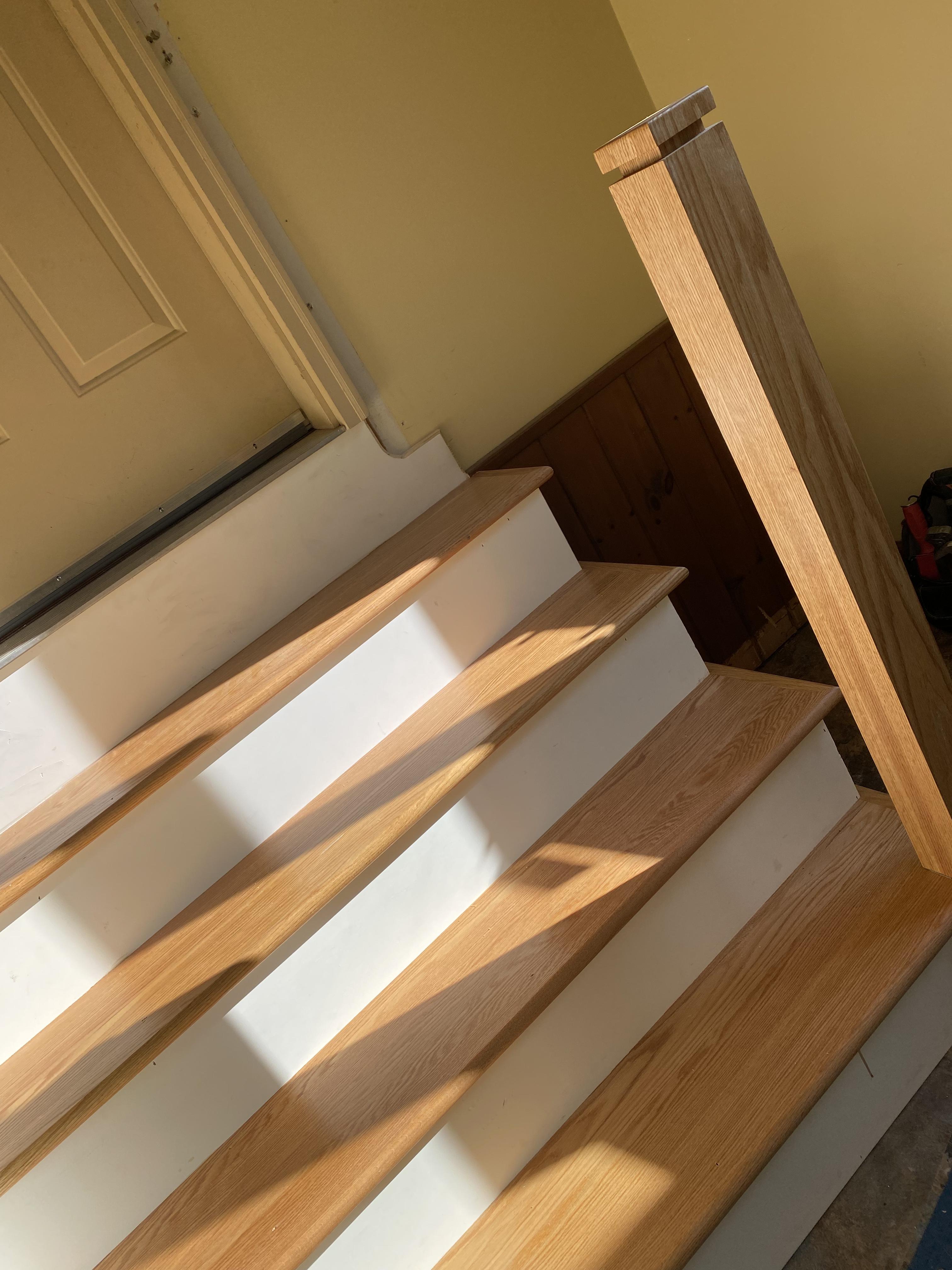 After — natural oak handrail and newel post detail on custom staircase remodel