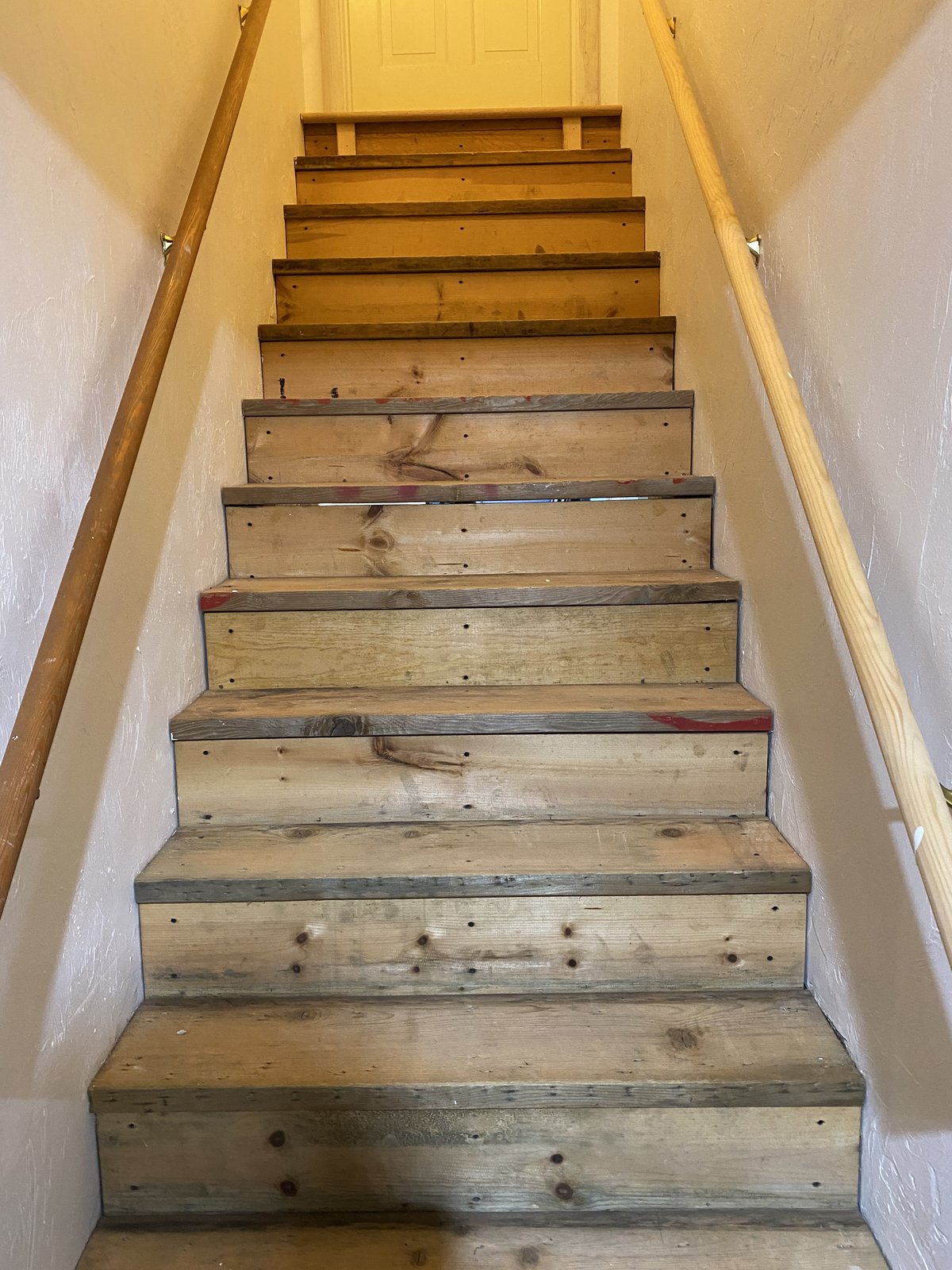 Cranston RI staircase — temporary timber treads and risers with nail holes and red layout markings before white oak renovation