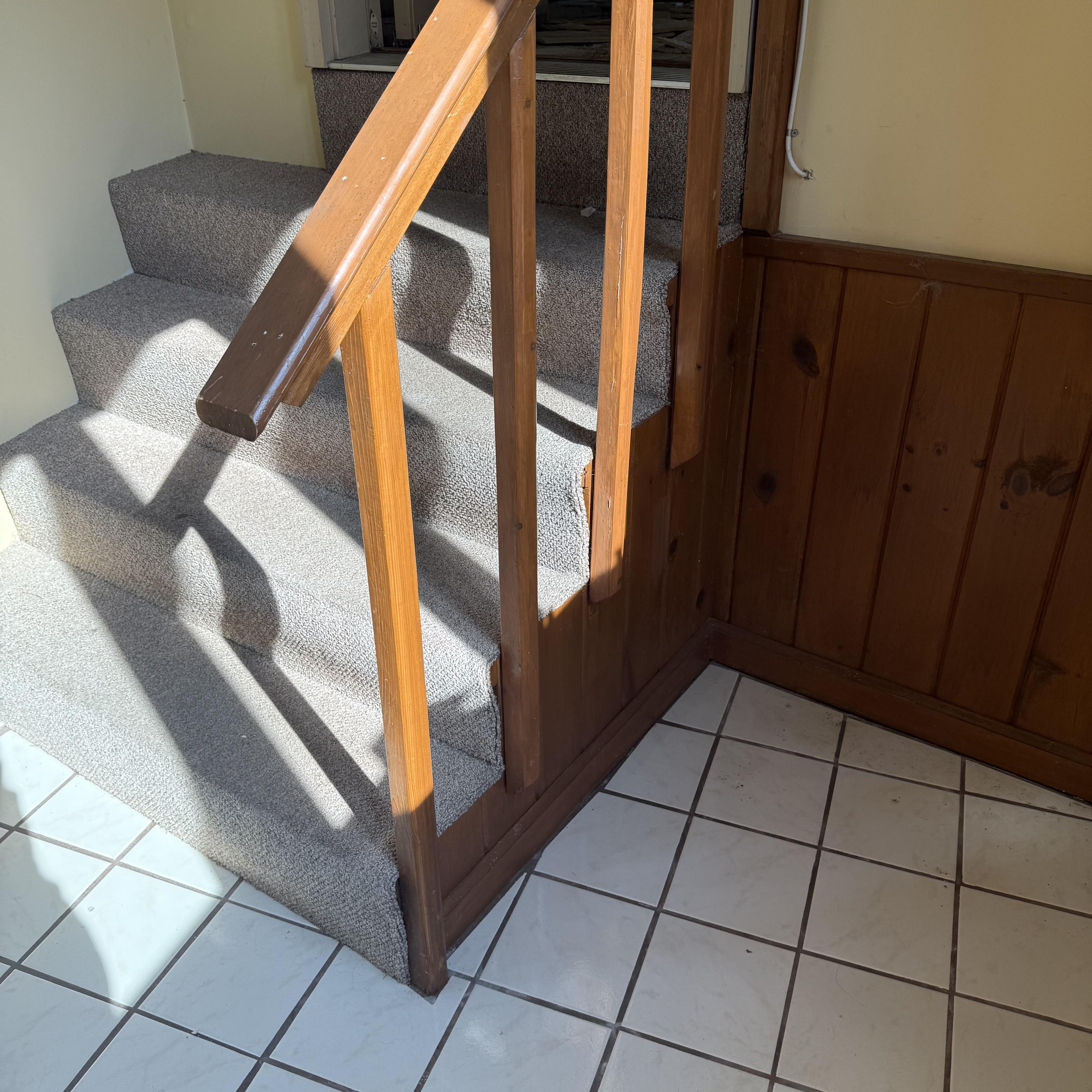Before — worn wooden railing and carpeted treads prior to custom staircase renovation