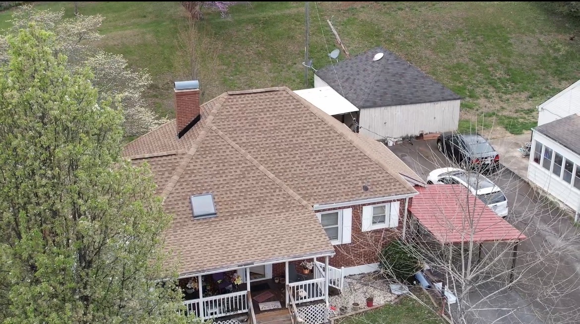 Aerial drone view of brick home with brown shingle roof replacement