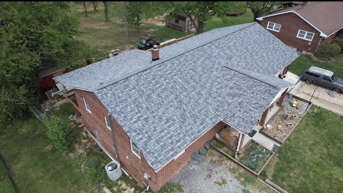 Aerial drone view of brick home with new gray shingle roof