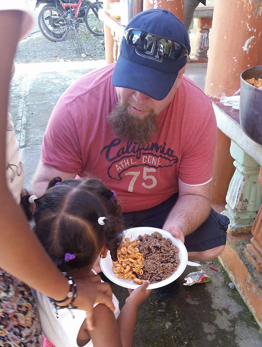 Brian Straley feeding a young Dominican girl lunch during a community visit in Barahona