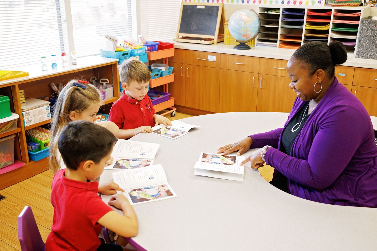 A Valley Prep teacher works through a reading lesson with three students at a round table