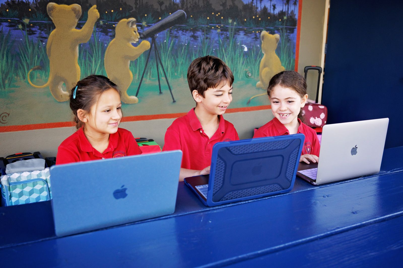 Valley Prep lower school students work on laptops beneath the campus lion mural