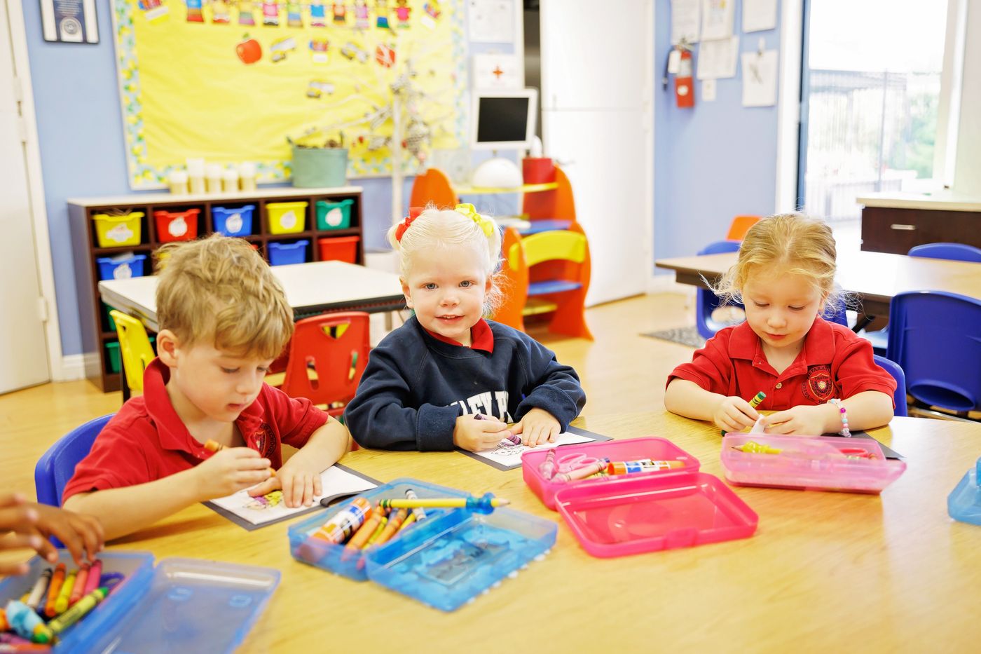 Preschool students colour together at a shared table at Valley Prep