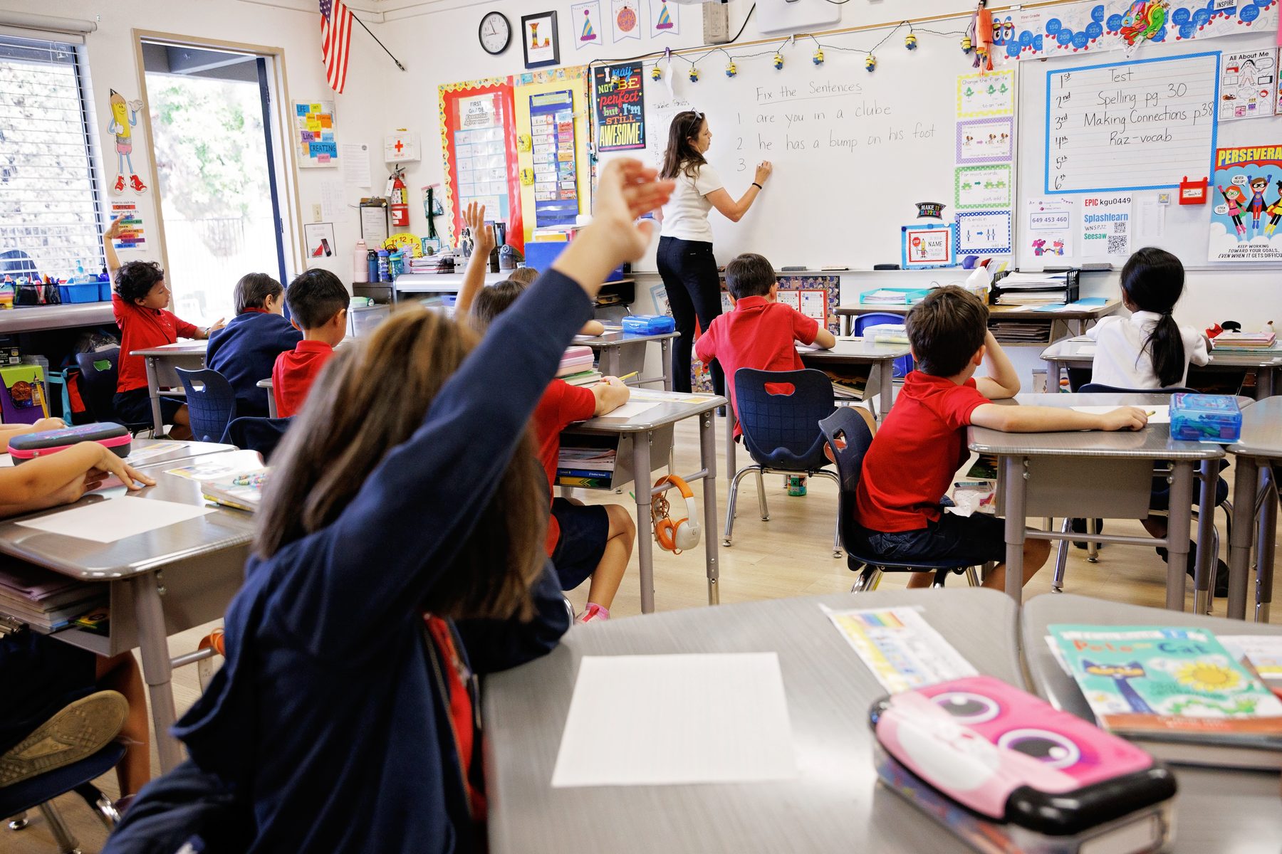 A first-grade student raises her hand during a lesson at Valley Prep