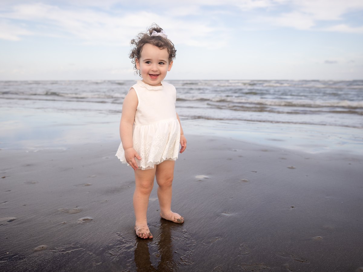 Smiling child standing on the wet sand at the beach