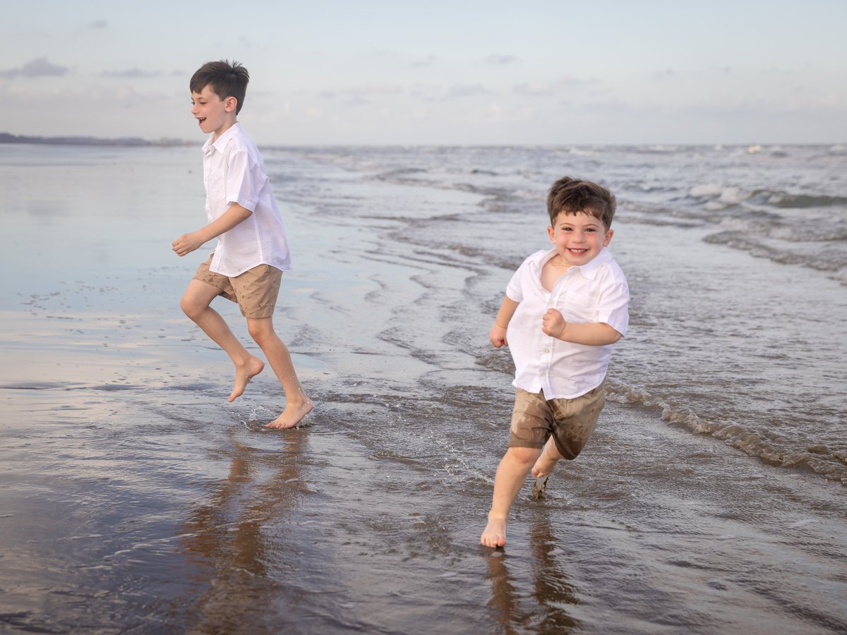 Two boys running barefoot through the shallow water