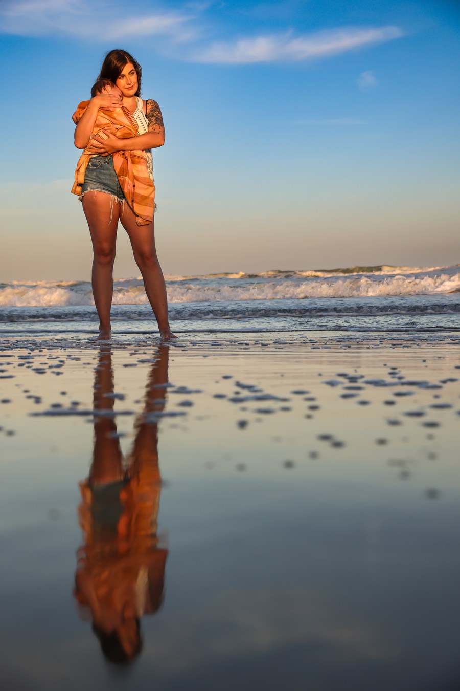 Mother holding her baby in the water at golden hour