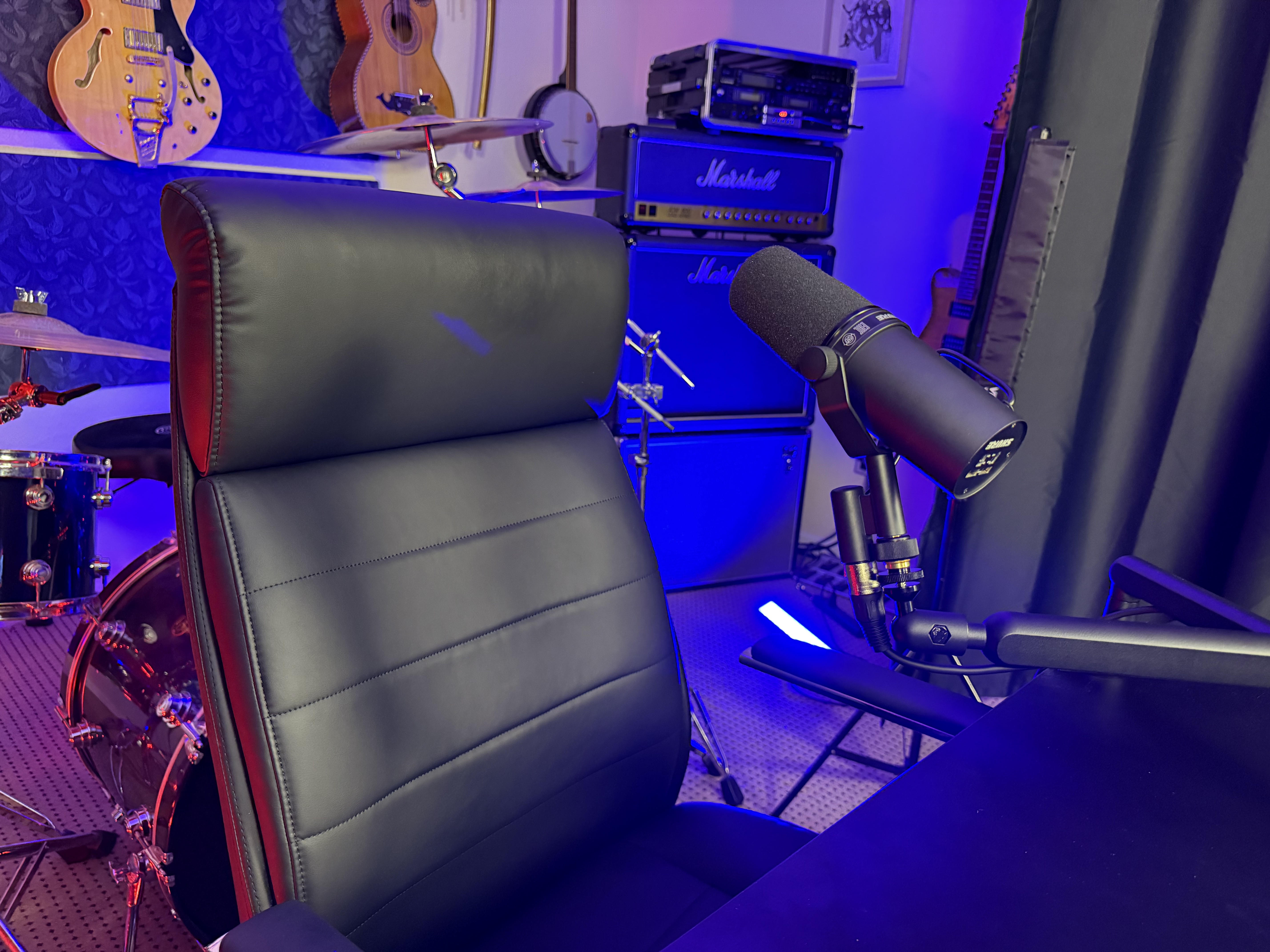 Professional broadcast microphone with blue studio lighting and Marshall amplifiers