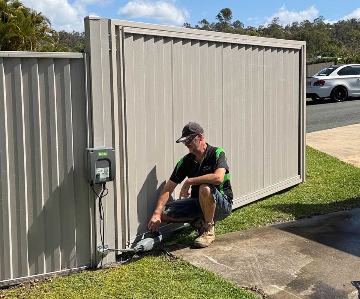 Matt inspecting a Merlin swing gate motor and control box during installation on the Gold Coast
