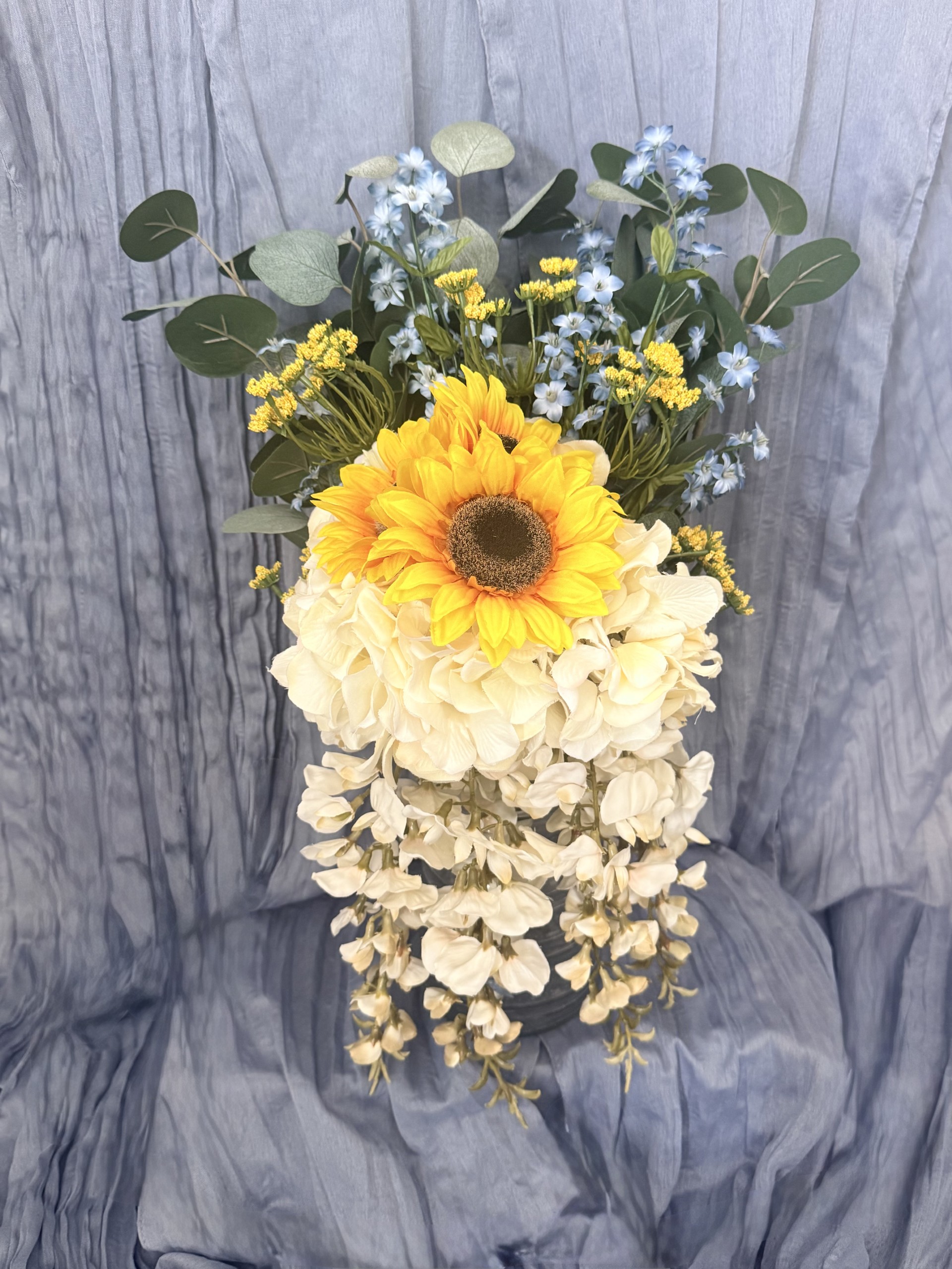 Cascading bridal bouquet with sunflower, white hydrangeas, wisteria, eucalyptus, and blue accents by Petal Essence in Dallas-Fort Worth