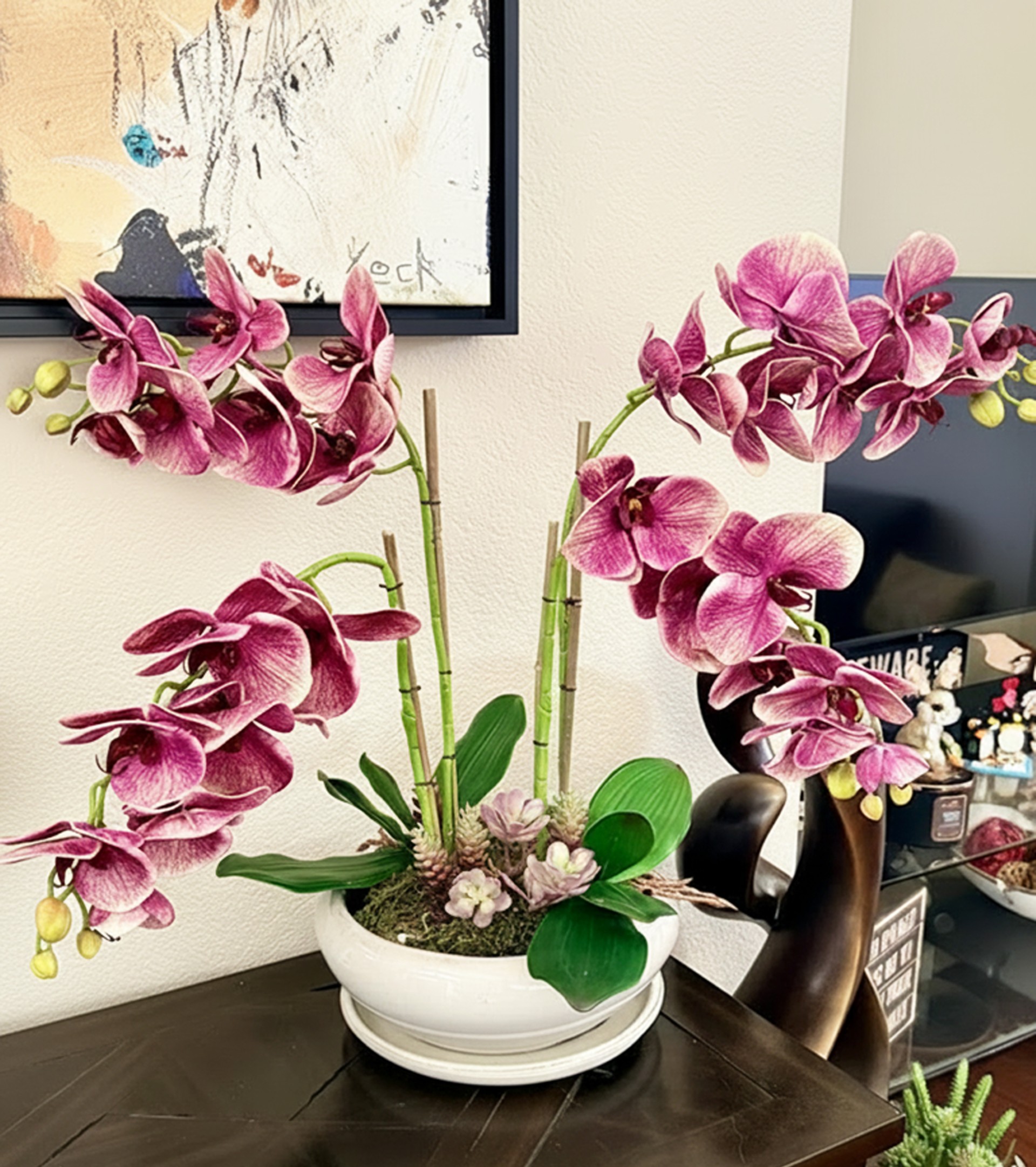 Pink orchid arrangement with bamboo accents and succulents in white bowl by Petal Essence in Dallas-Fort Worth