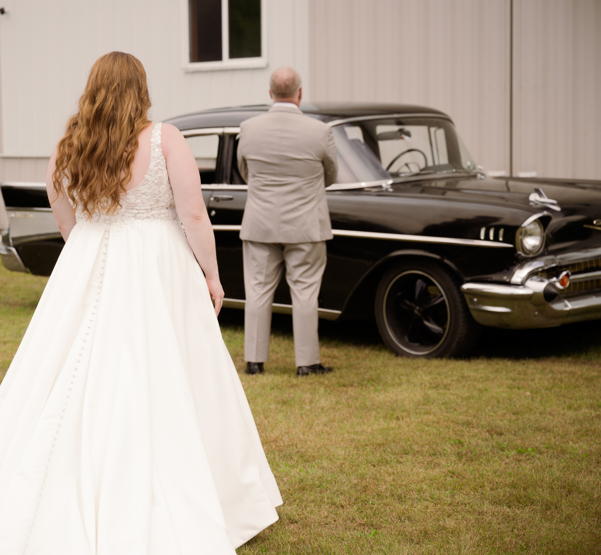 Bride approaching groom at classic car