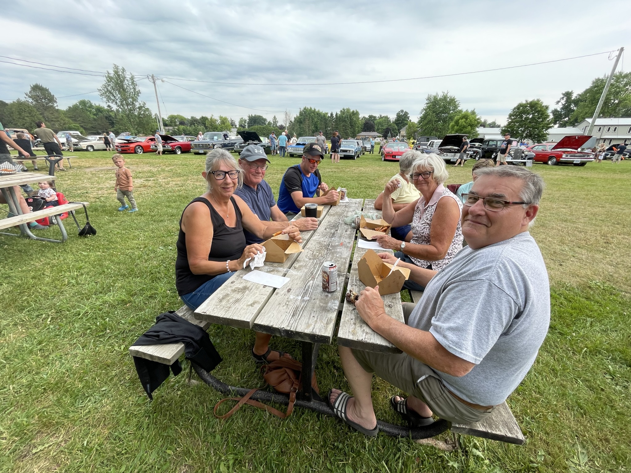 Families enjoying food at a classic car show