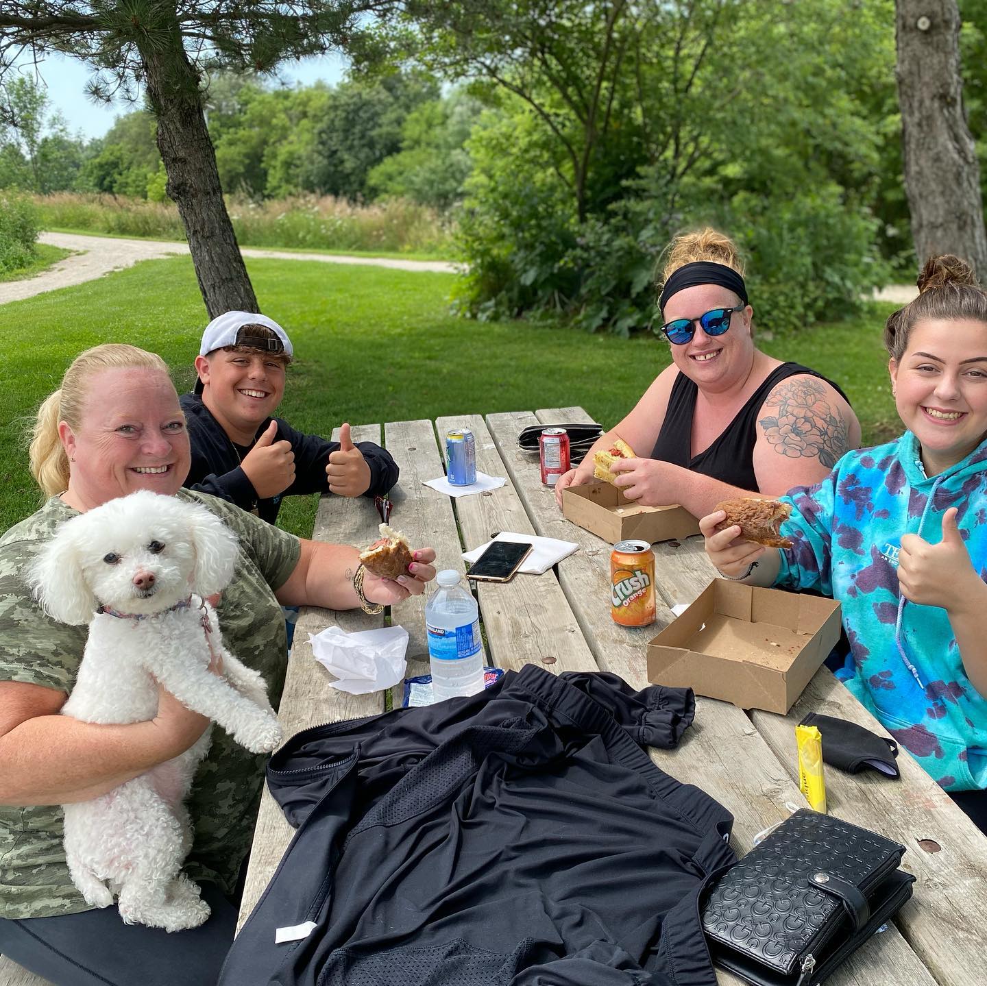 Friends and their pup enjoying hot dogs at a picnic table