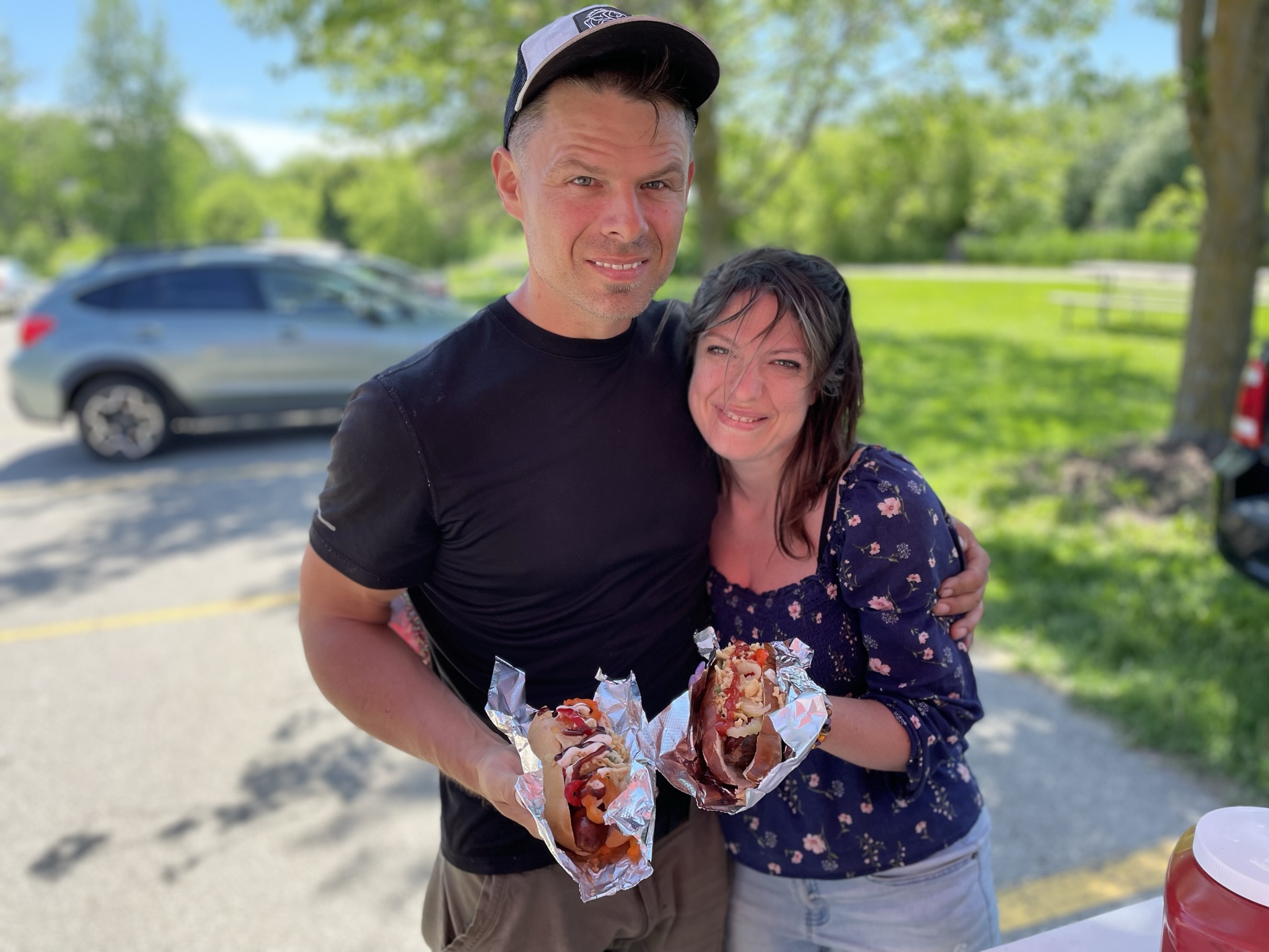 Couple showing off their loaded hot dogs