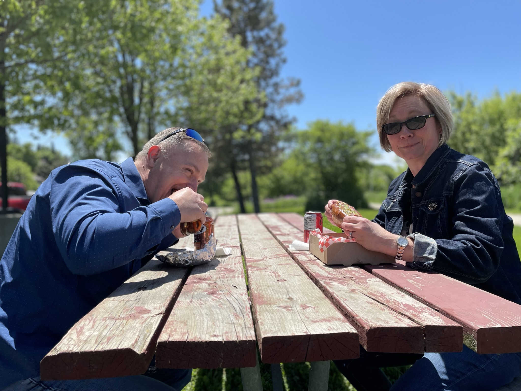 Couple digging into hot dogs on a sunny day