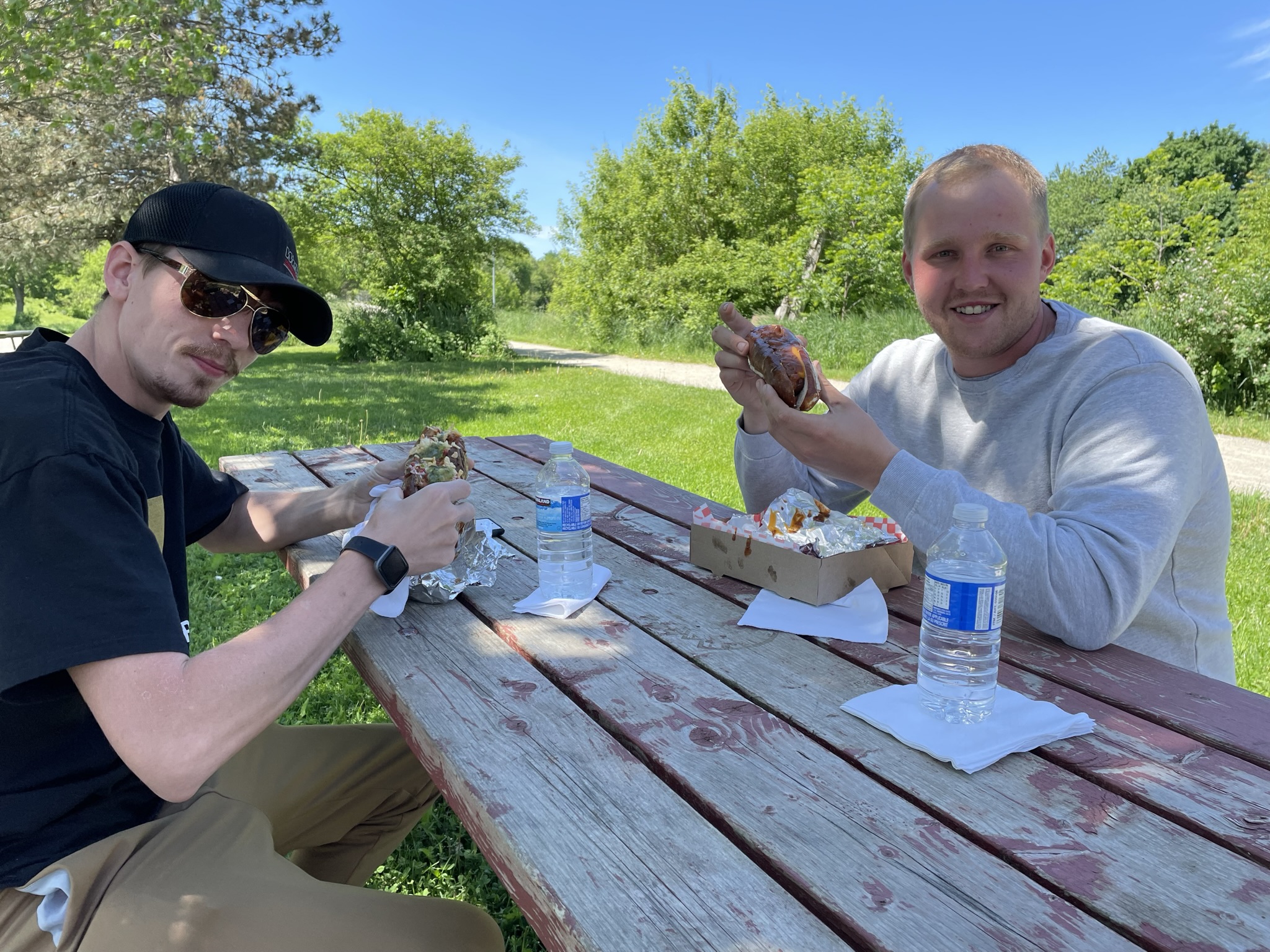 Customers enjoying gourmet hot dogs at a picnic table