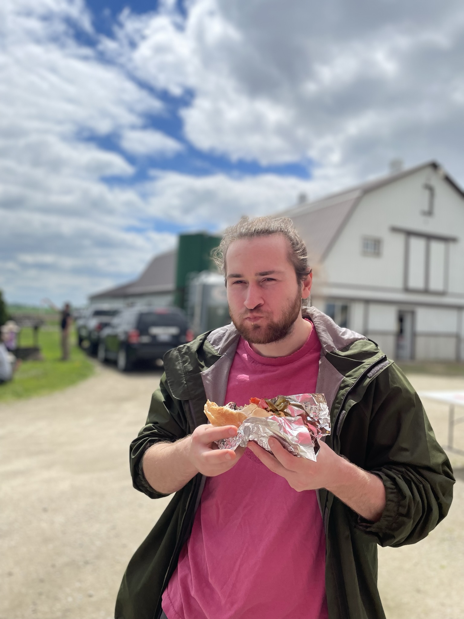 Customer enjoying a loaded hot dog at a farm event