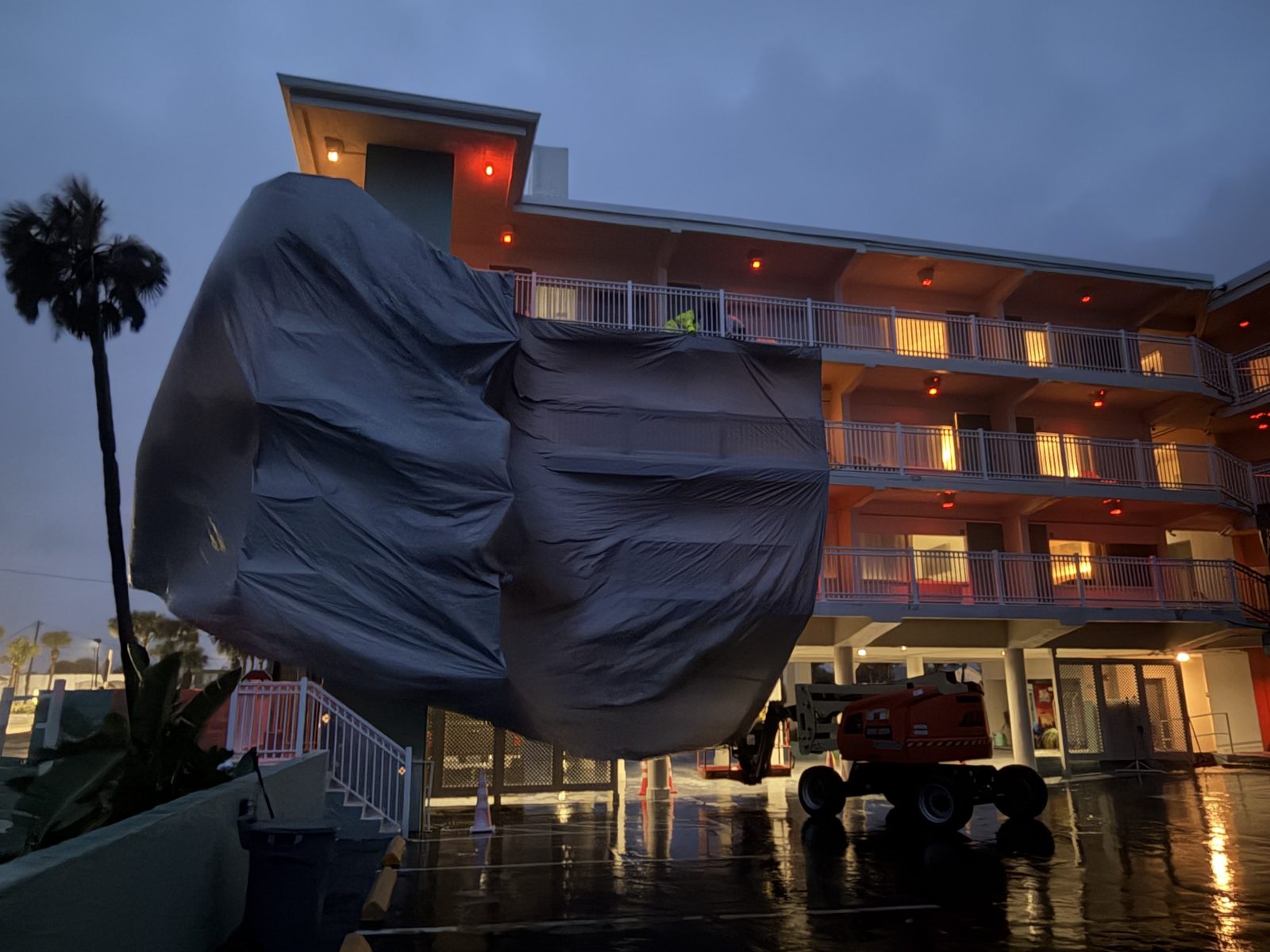 Chateau Mar Resort stair tower wrapped in containment tarps at dusk with the lift in front