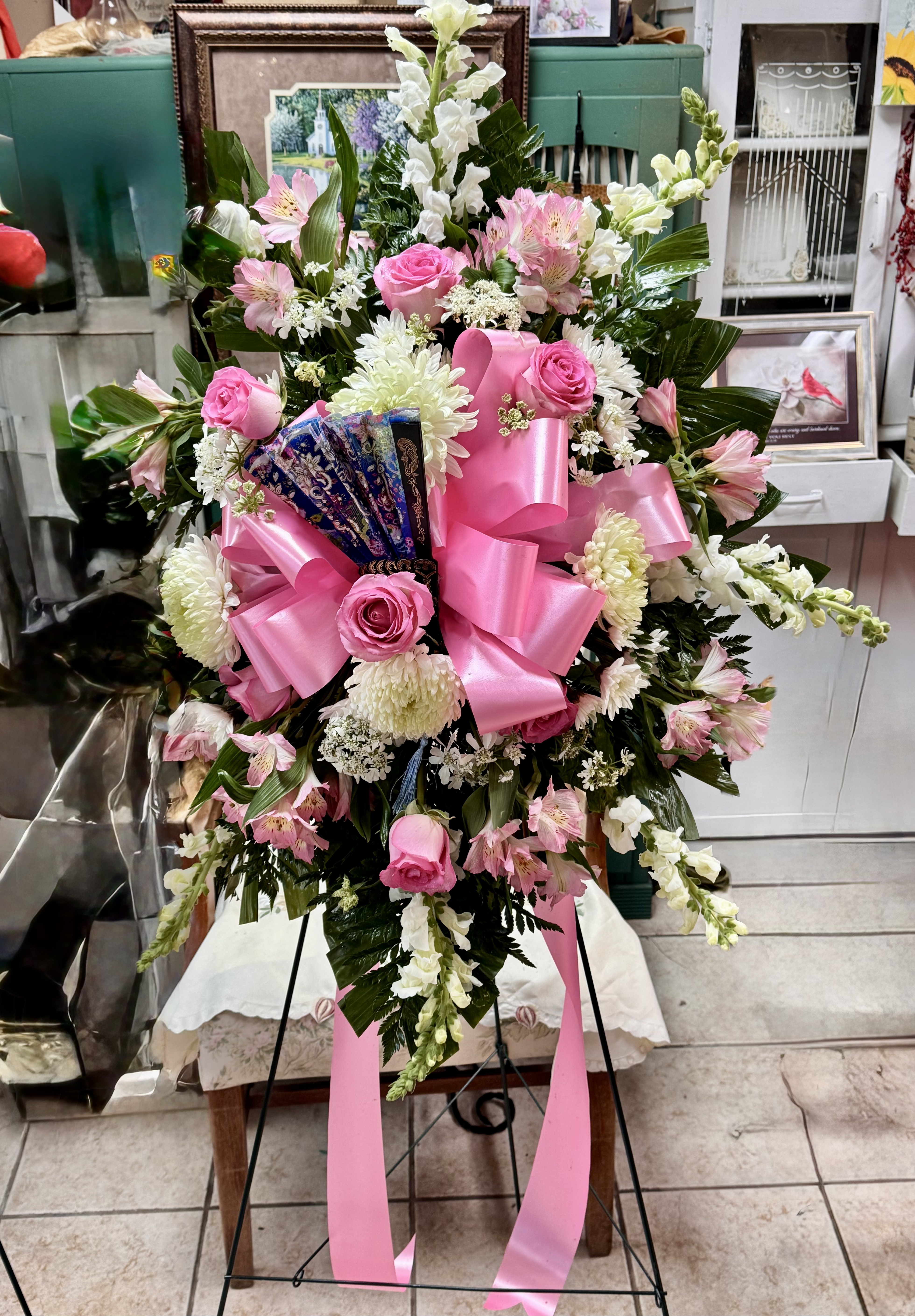 Pink and white sympathy spray with pink ribbon and decorative fan
