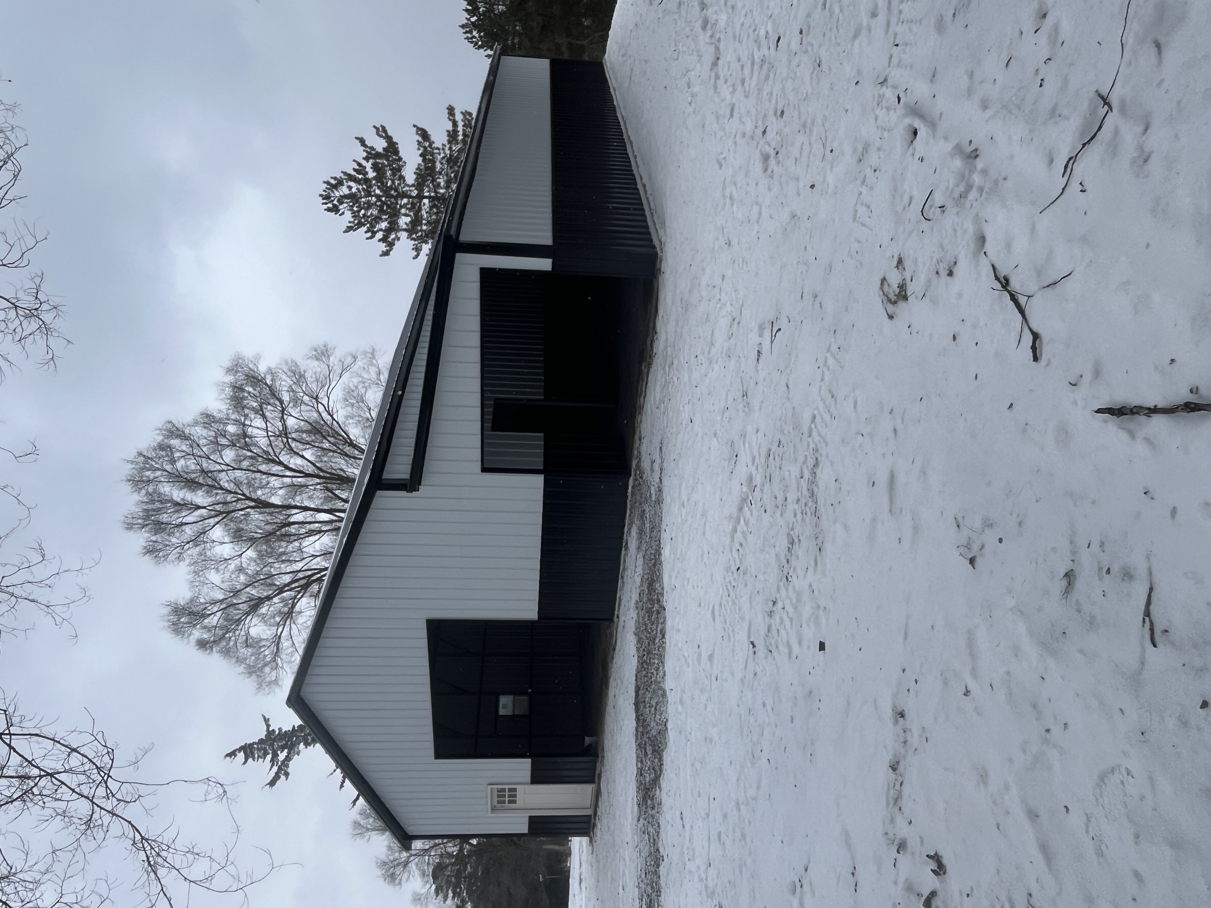 White and black two-tone steel building with large open bay doors in snowy winter