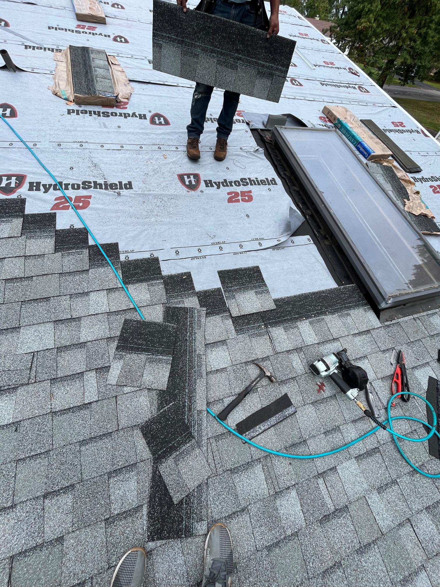 Crew installing shingles with underlayment and skylight Pittsburgh PA