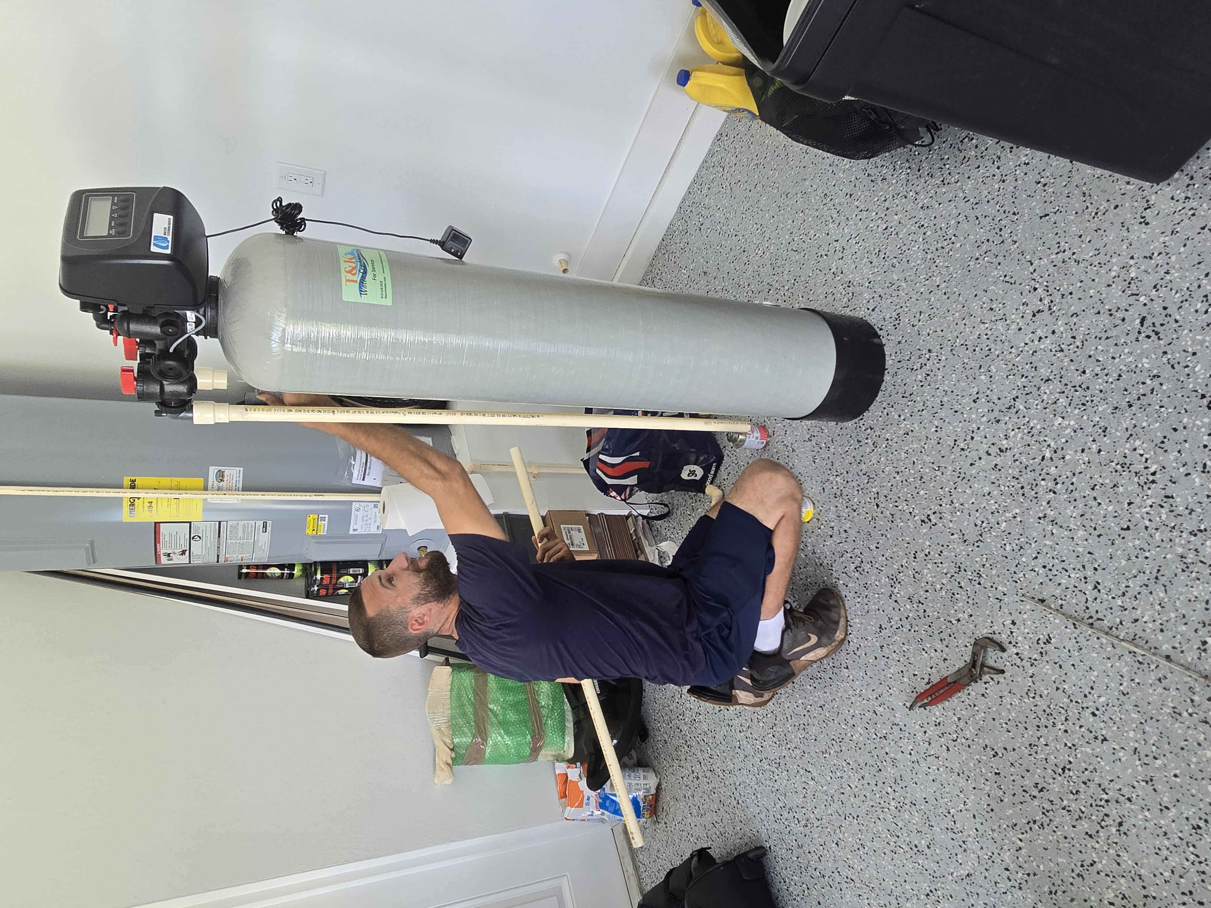 T&K Water Conditioning technician installing a water softener system in a Tampa Bay home garage