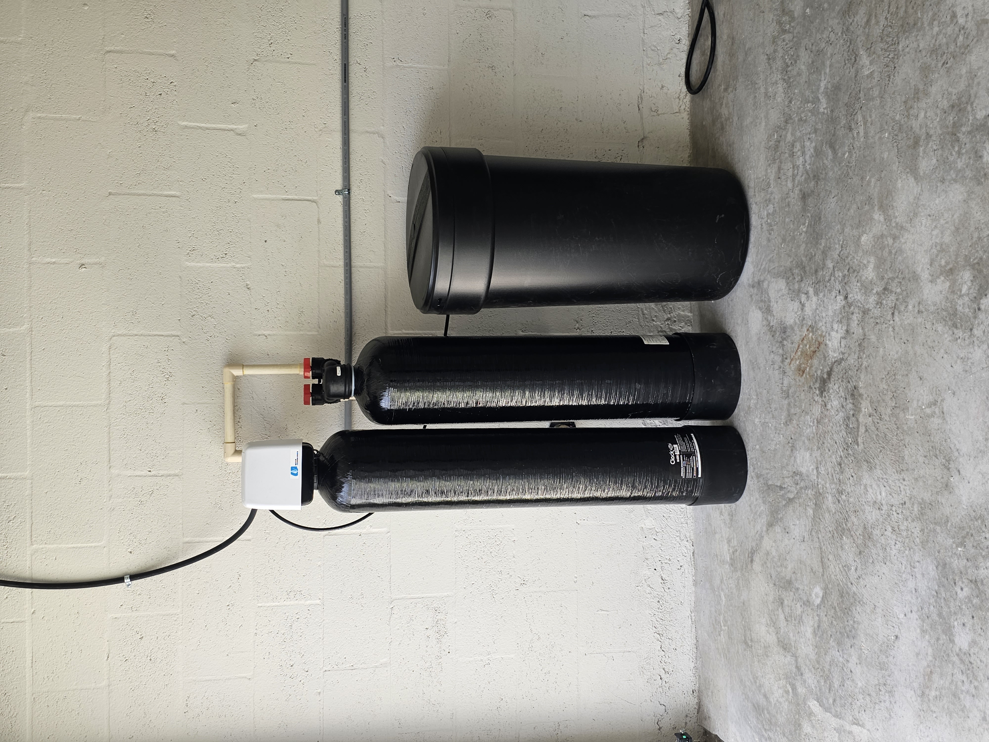 T&K Water Conditioning black dual tank softener system with large round salt tank in garage
