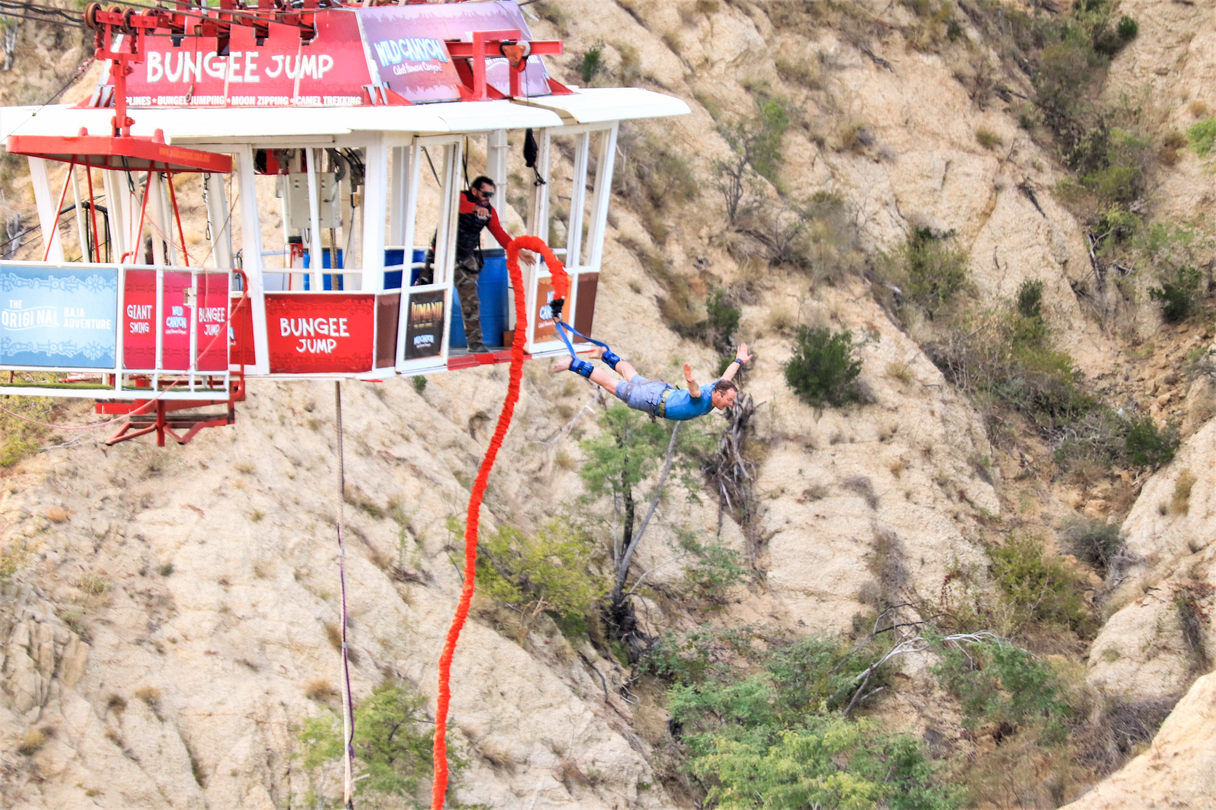 Bungee jumper mid-fall from Wild Canyon's glass-floored gondola above Baja canyon