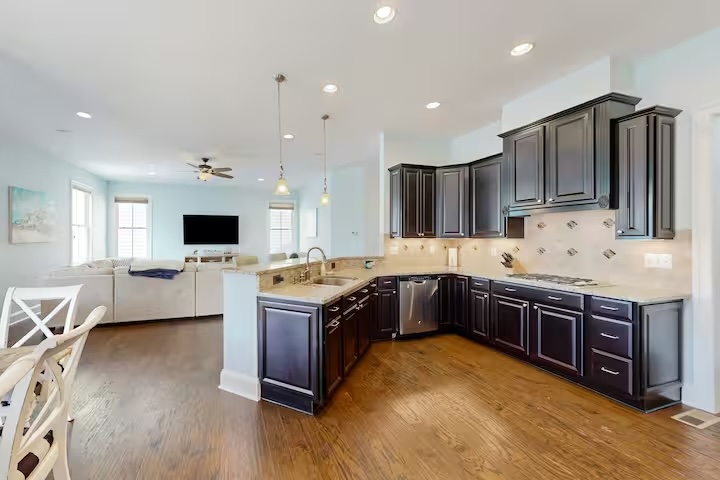 Open kitchen with dark cabinets pendant lights and living area