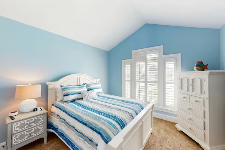 Blue bedroom with vaulted ceiling white furniture and striped bedding