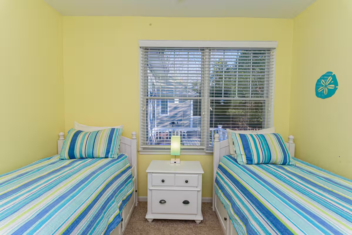 Sunny yellow twin bedroom with striped bedding and sand dollar decor