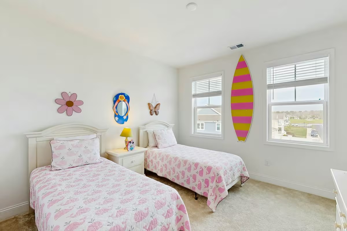 Playful twin bedroom with pink whale bedding and surfboard decor