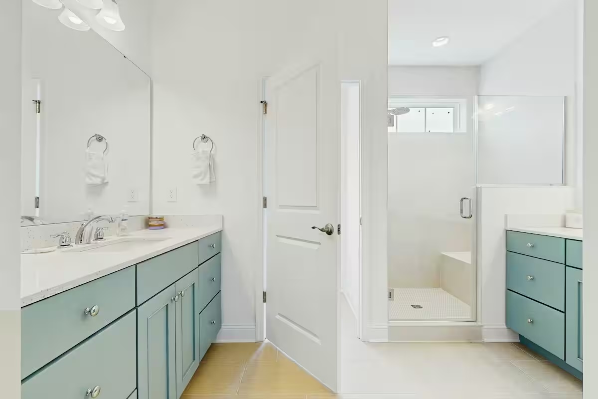 Spa bathroom with teal vanity cabinets and glass shower