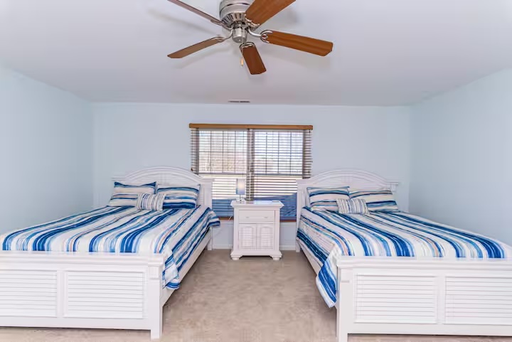 Twin bedroom with blue striped bedding and ceiling fan