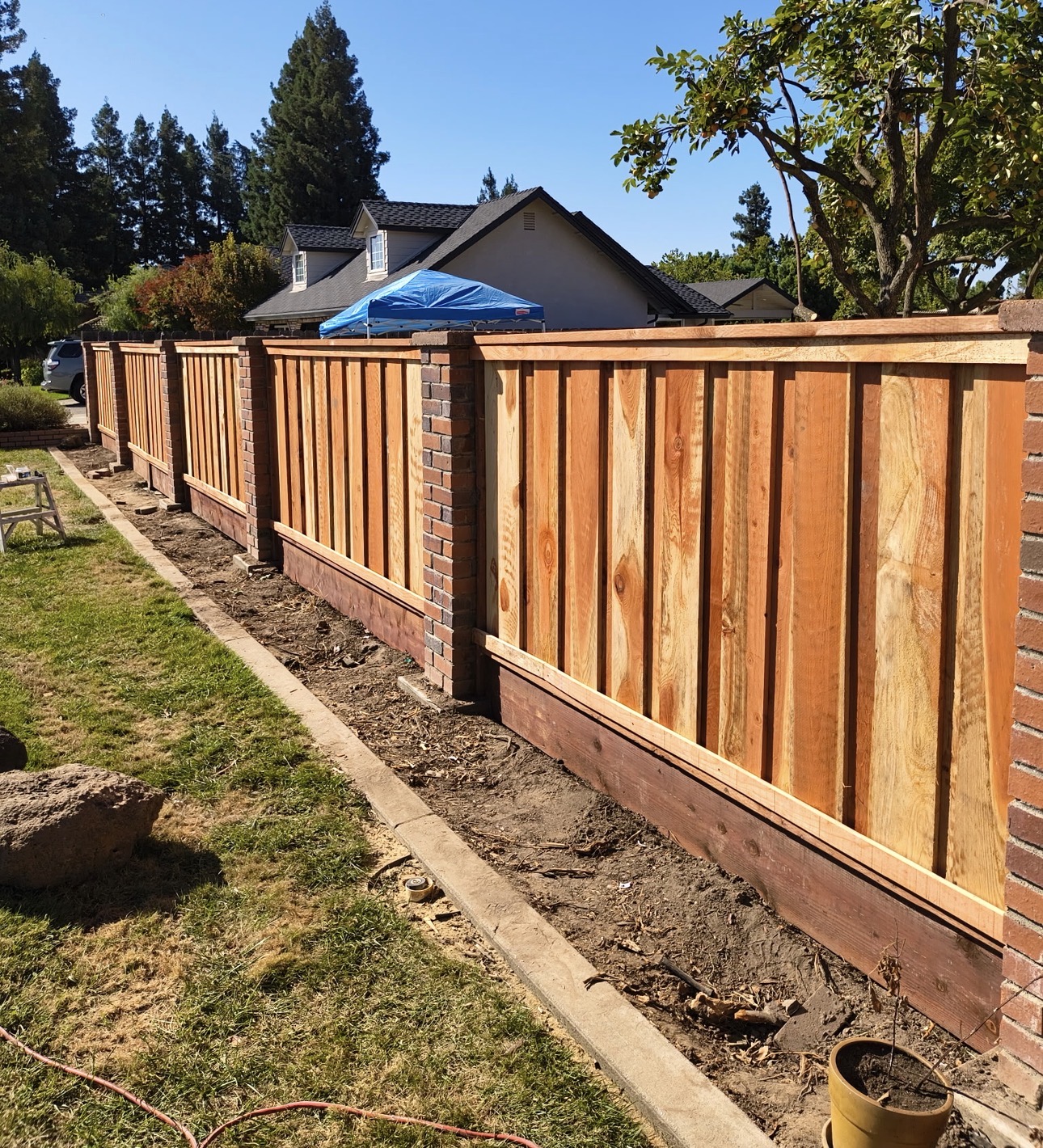 Wood fence installation with brick pillar accents