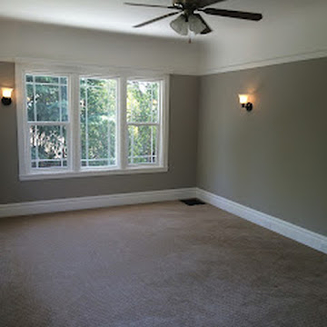 Interior master bedroom painting - warm gray walls with white crown molding and bay window