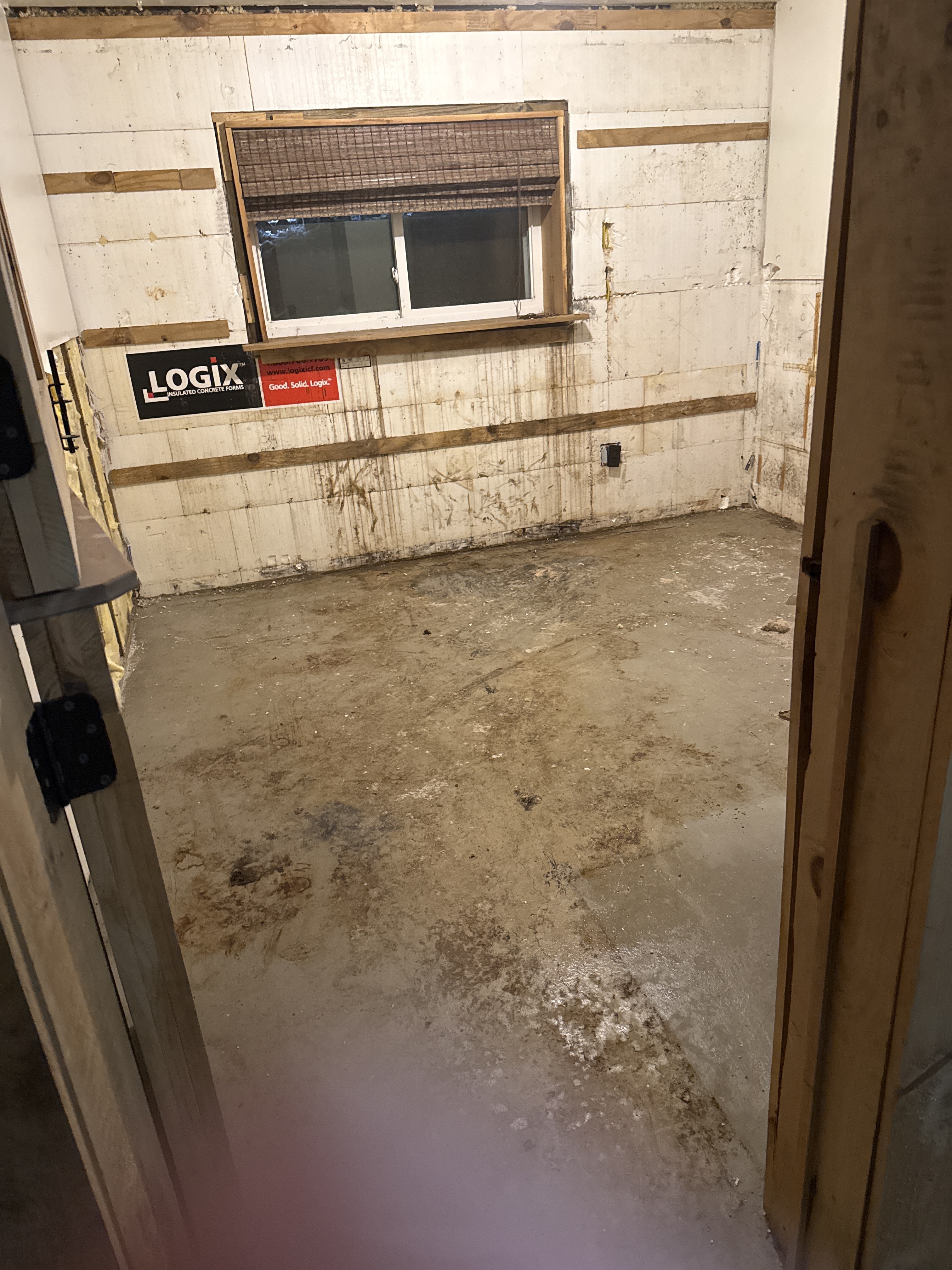 Basement room with bare concrete floor and exposed insulated concrete form walls after removal of finishes