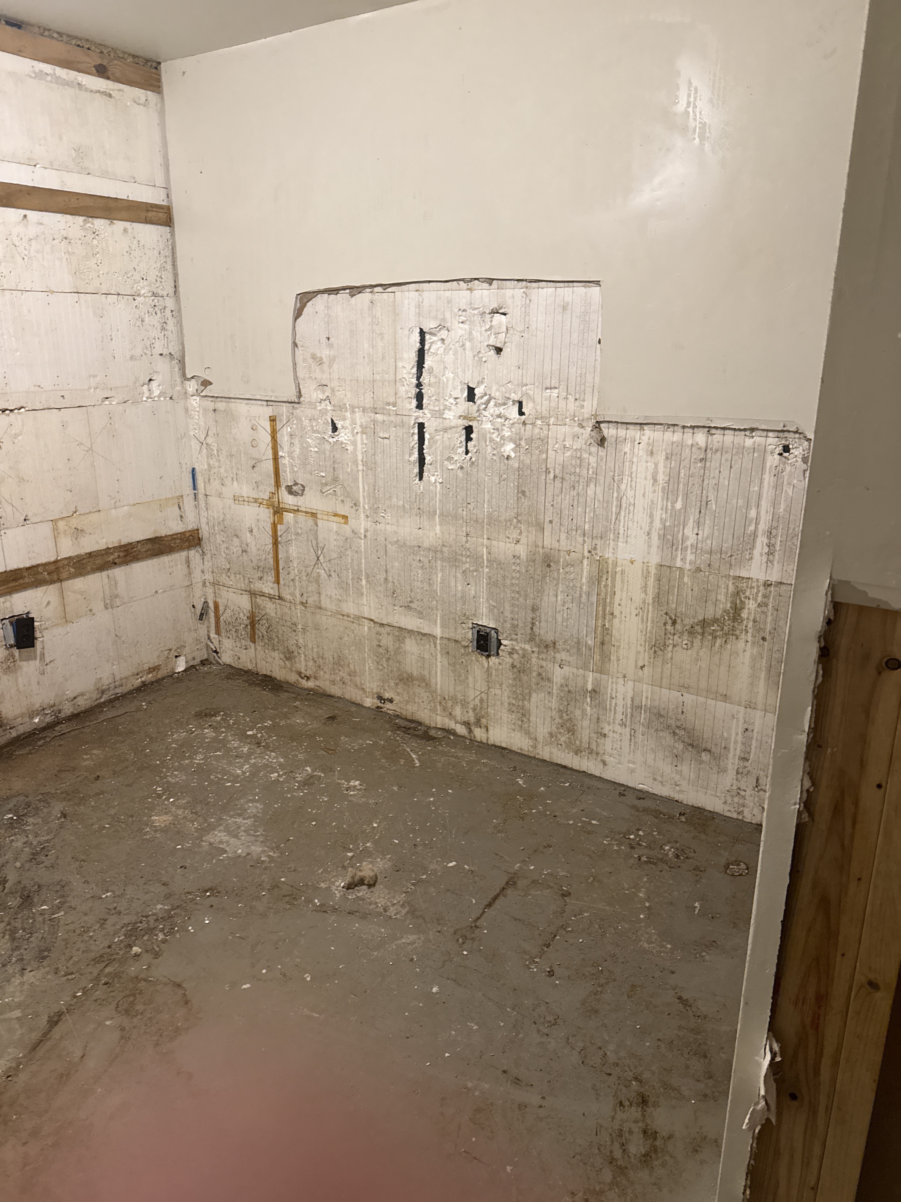 Basement corner with a section of drywall cut away exposing the concrete form wall behind it