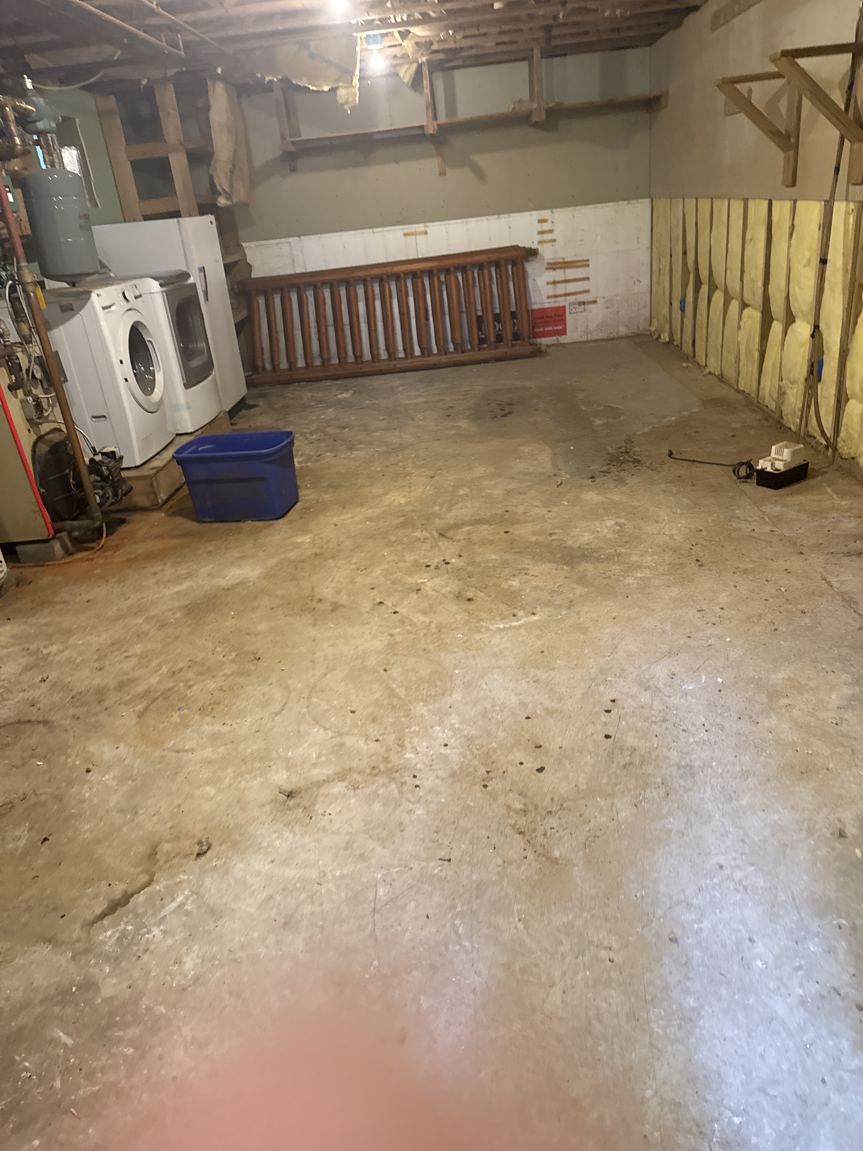 Basement utility area with laundry appliances, bare concrete floor, and exposed wall insulation