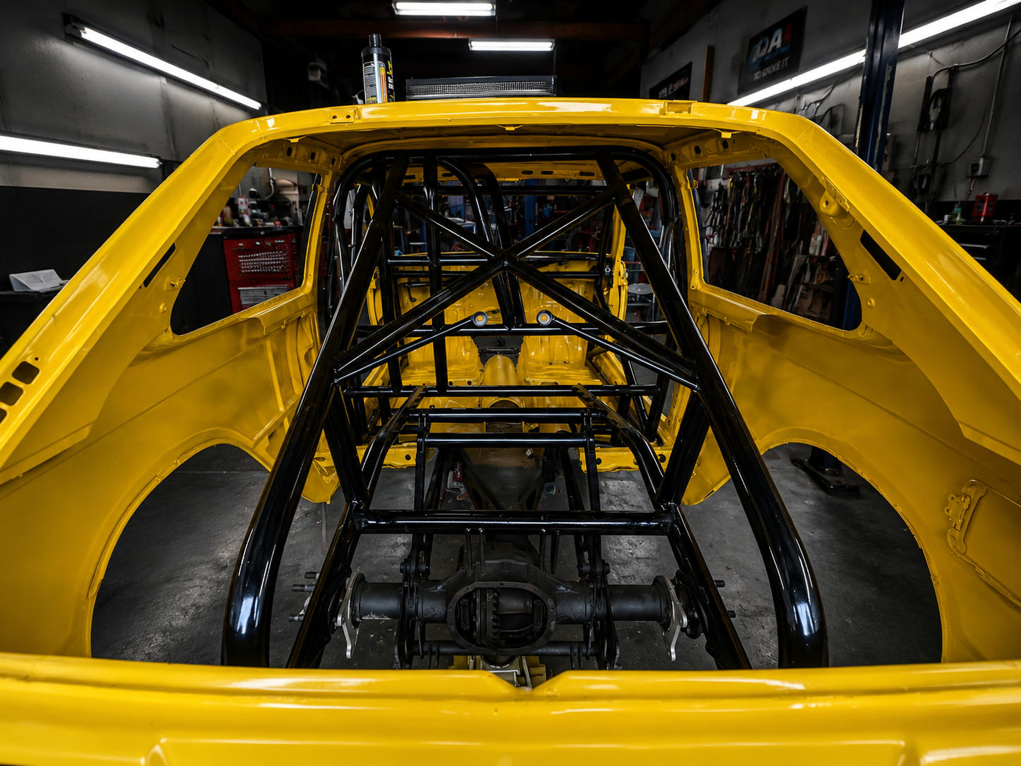 Yellow race car roll cage rear view at J&J Imports shop