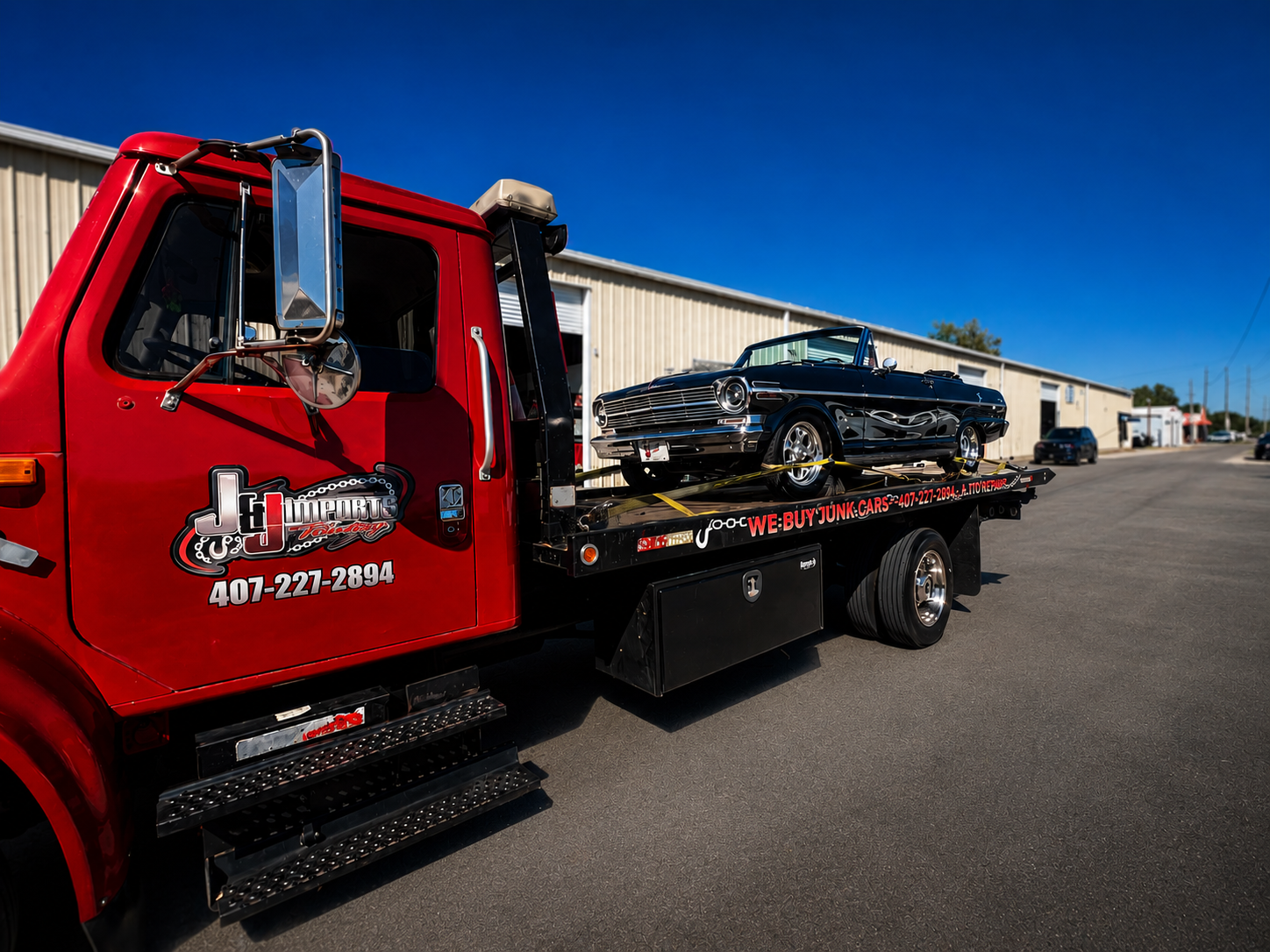 J&J Imports tow truck hauling a classic black convertible