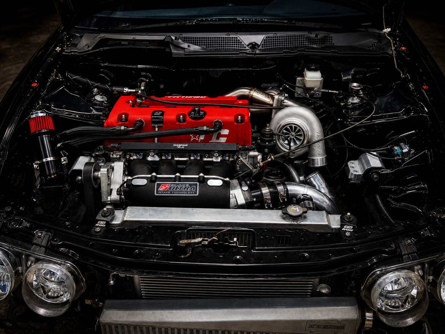 Turbo engine bay with red valve cover and Skunk2 intake at J&J Imports