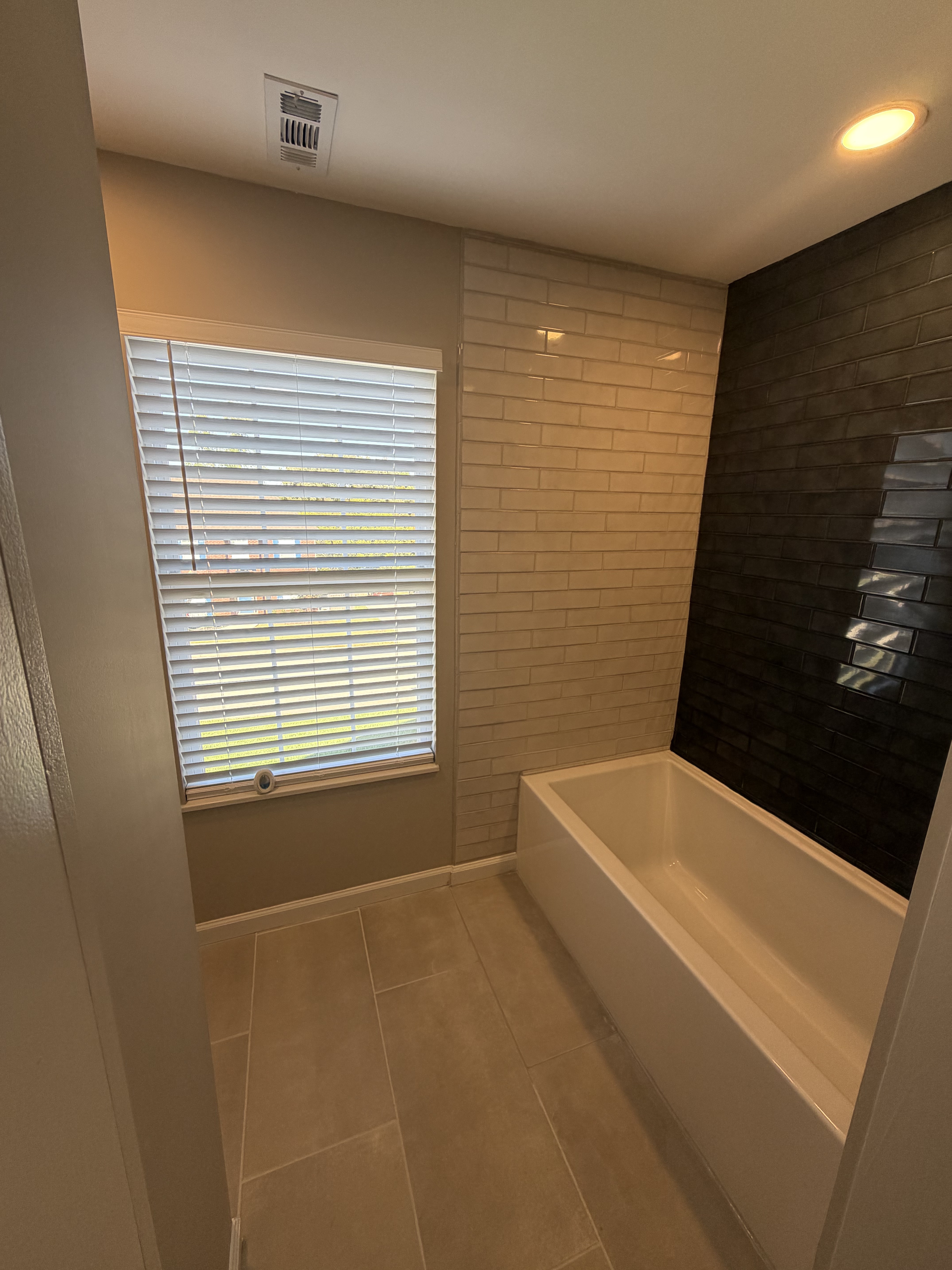 Tub area with navy accent tile and natural light from window
