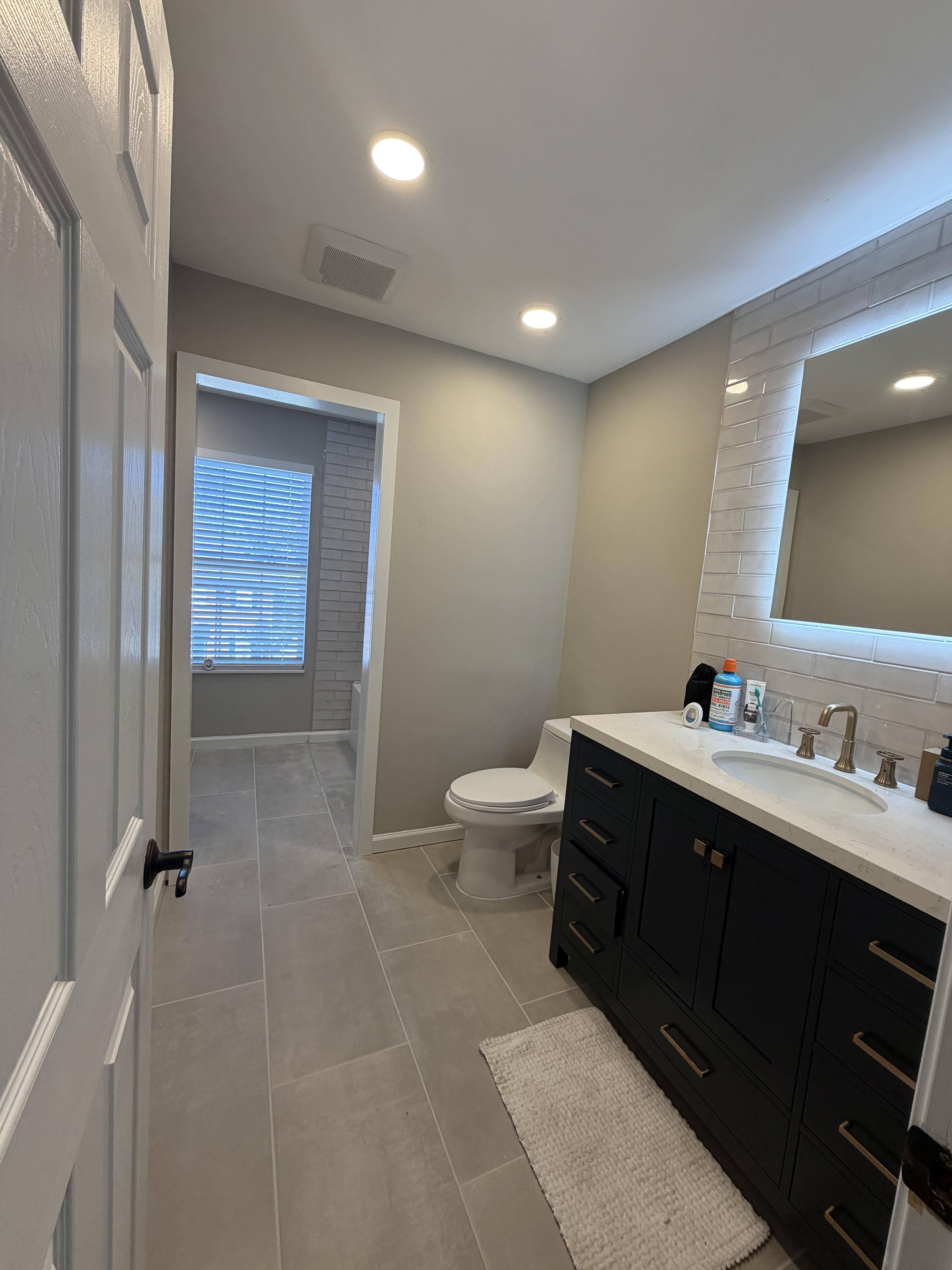 Bathroom overview with navy vanity, subway tile, and bronze fixtures
